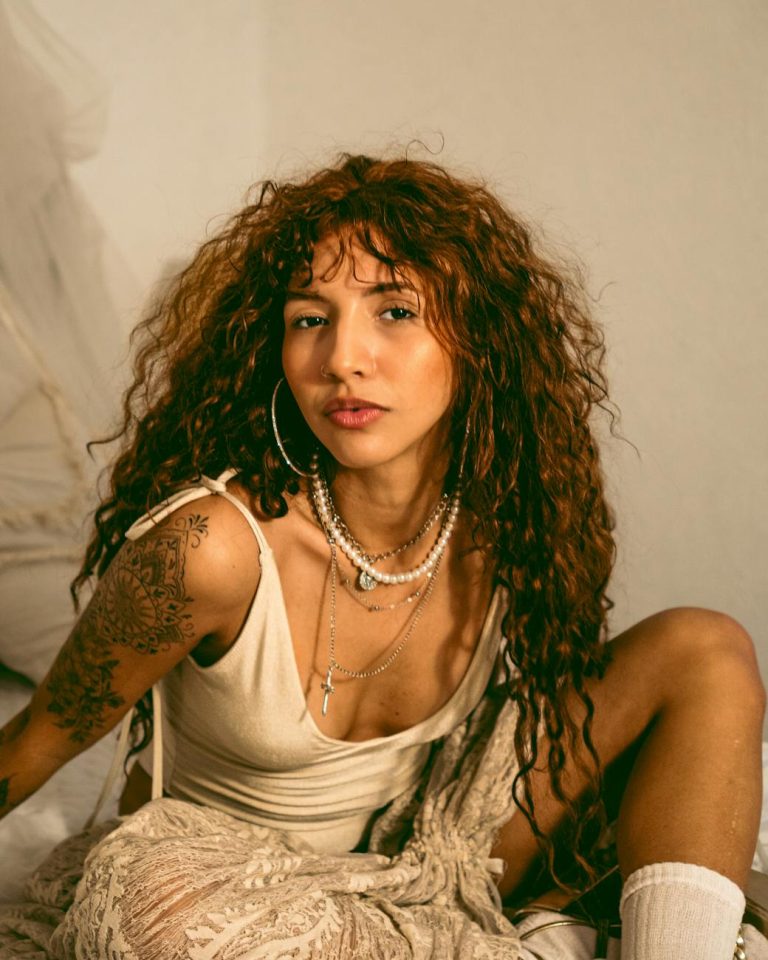 portrait of a stylish woman with curly hair and tattoos