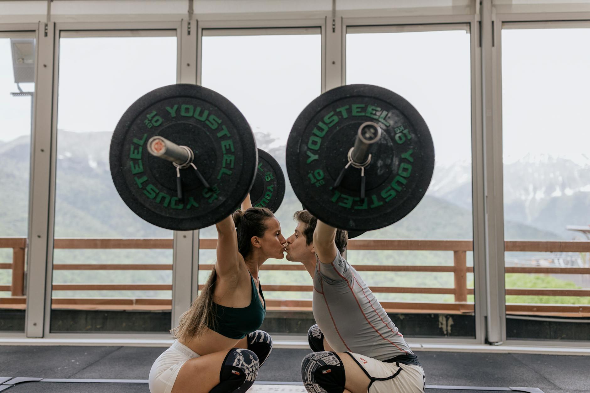 couple kissing while lifting barbells
