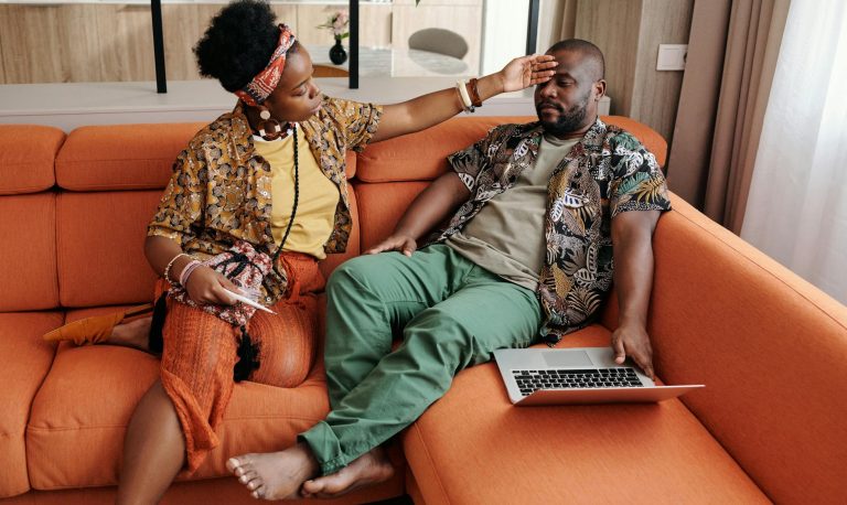 man and woman sitting on orange sofa