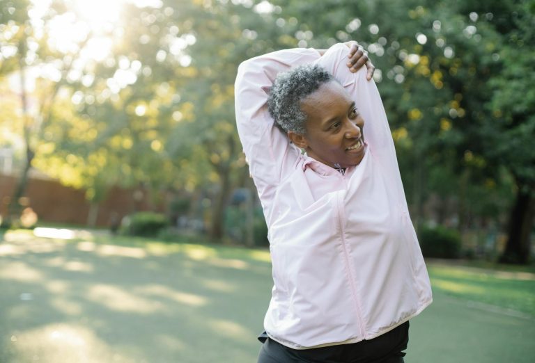 elderly man in pink jacket stretching her hands